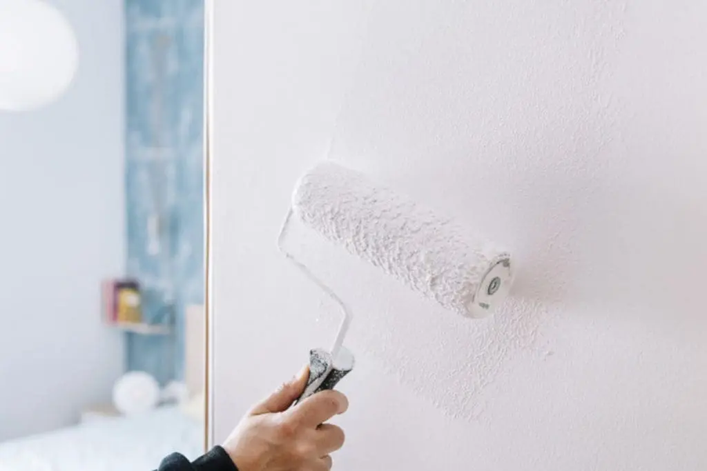 Why interior paint prep work determines how long it lasts — painter rolling white paint onto a properly prepared interior wall